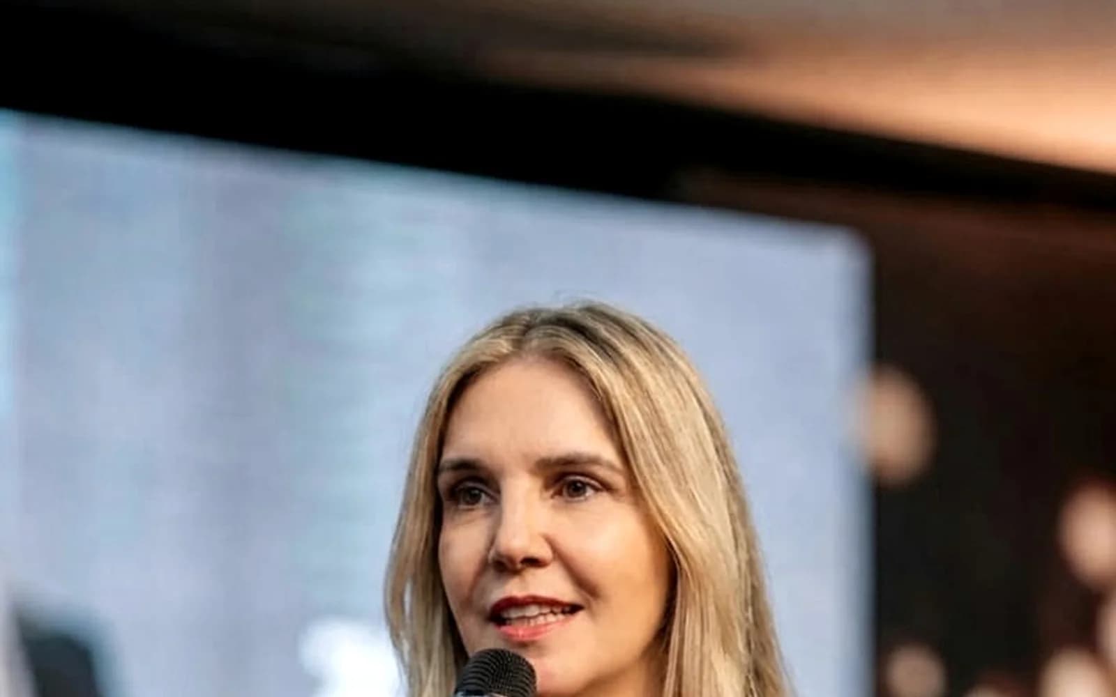 Andréa Boggio falando ao microfone em uma palestra