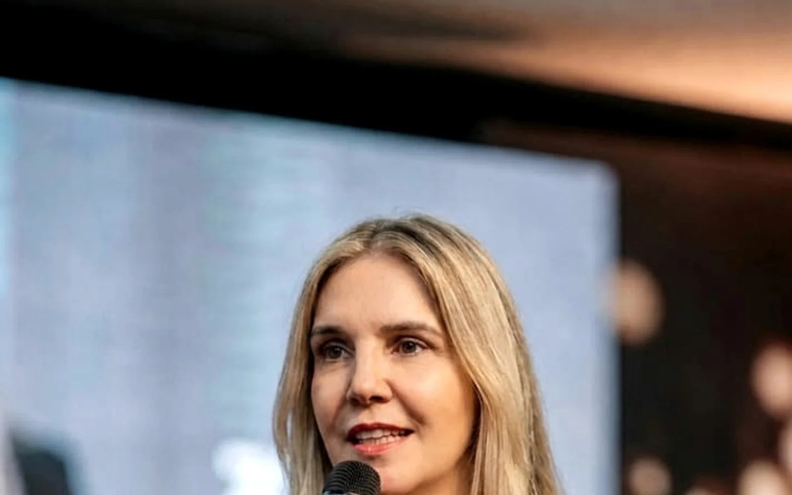 Andréa Boggio falando ao microfone em uma palestra